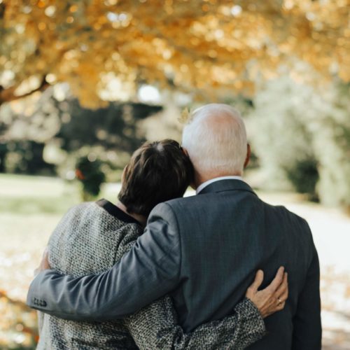 elderly couple leaning on each other