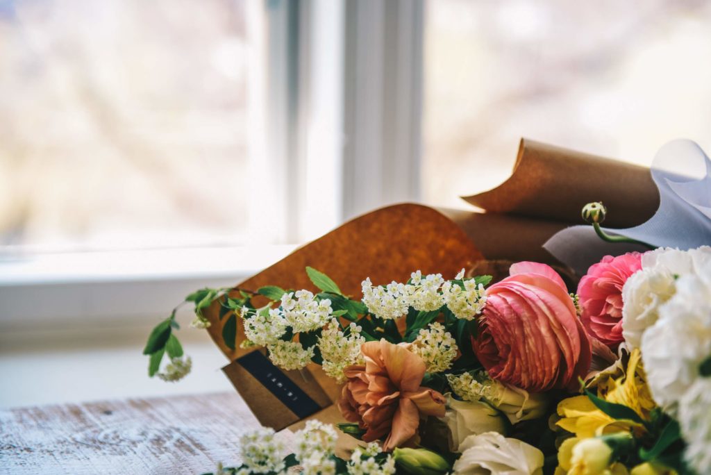 Bouquet of flowers on table in front of white, airy light window