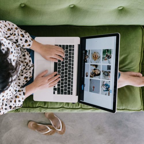 girl sitting on green couch using laptop