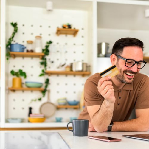 Man on his laptop in the kitchen learning money saving tips from swoosh finance