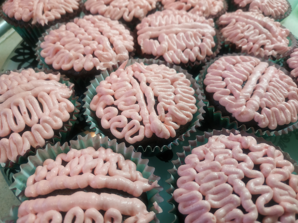 Chocolate cupcakes with pink pipped brains on top.