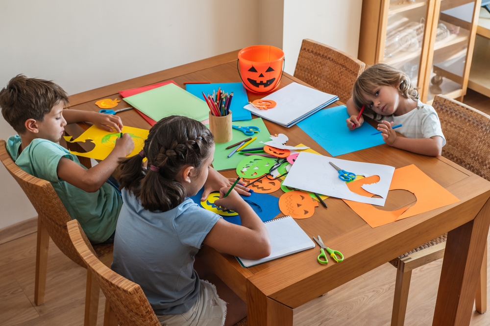 Kids having fun cutting out halloween shapes to decorate for the halloween party.