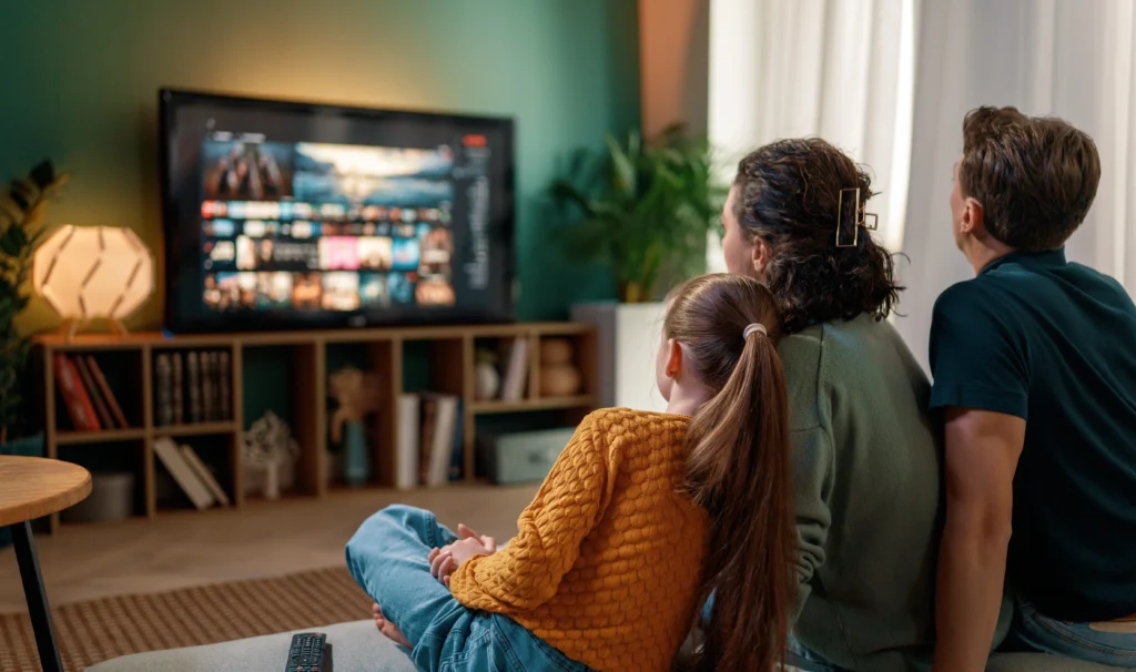 mother and father with daughter watching free streaming service cast to the TV in their living room