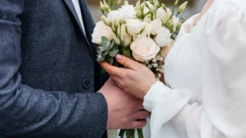 Close up of bride and groom's hands both holding flower bouquet at wedding | Are Wedding Loans a Good Idea?
