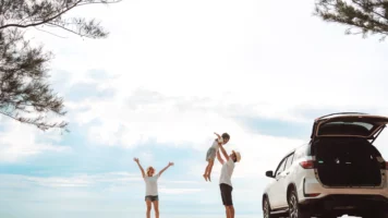 Young parents and their child celebrating a successful Labour Day road trip to a Queensland beach