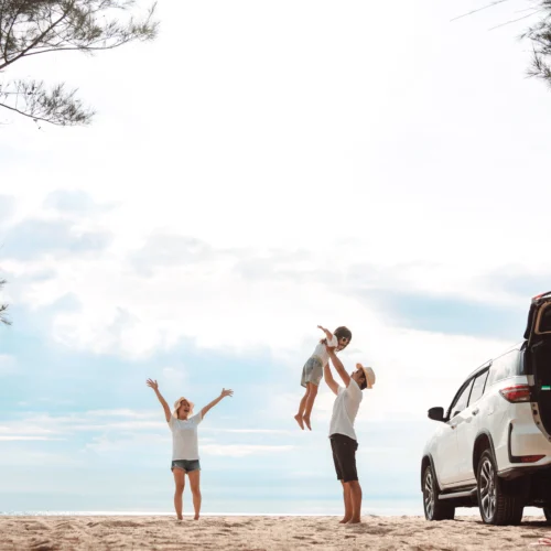 Young parents and their child celebrating a successful Labour Day road trip to a Queensland beach