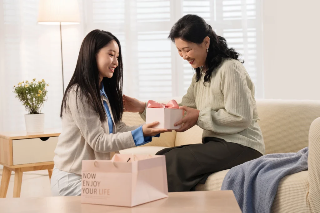 Adult daughter giving mother an aesthetically pleasing pink gift