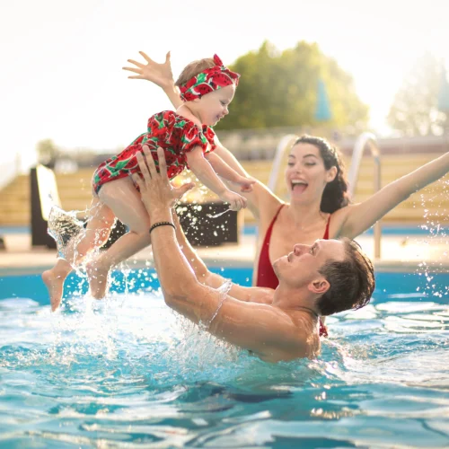 A mum and dad play with their baby in a new pool - how much will it cost to build a pool