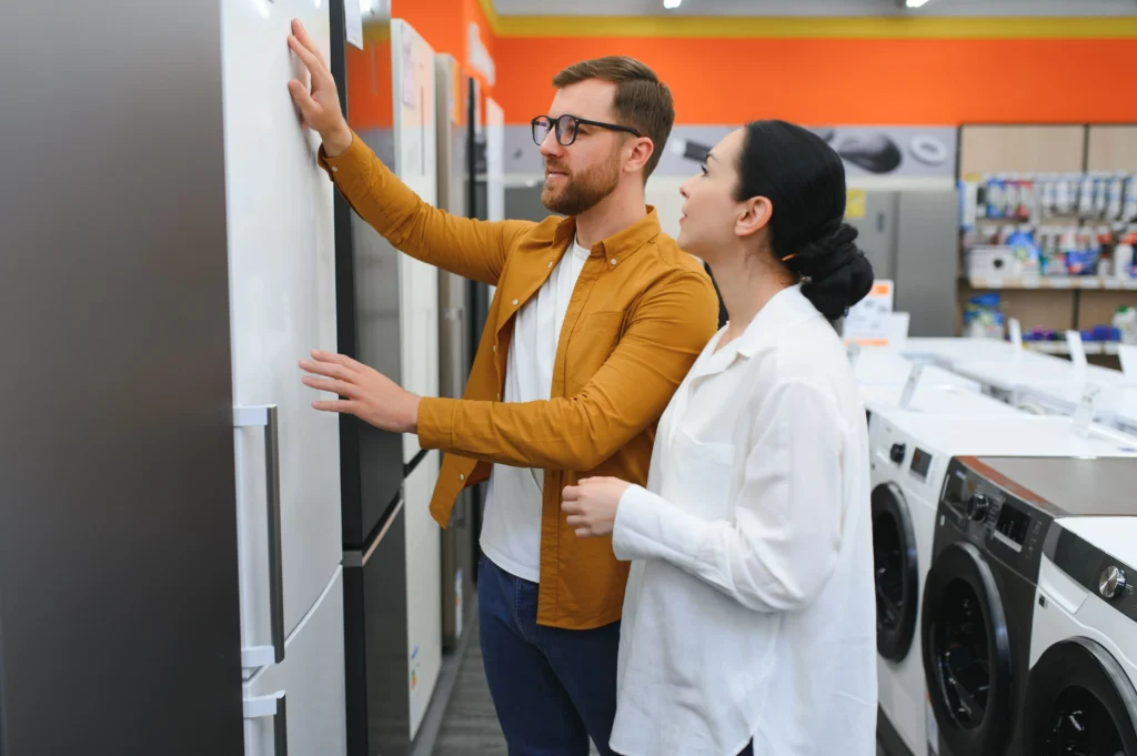 A couple in an appliance and furniture store looking at different fridges to spend their tax refund on