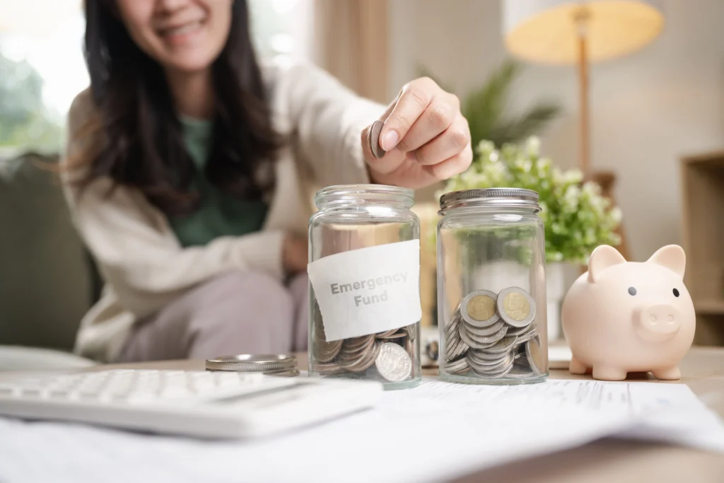 Woman sorting coins from her tax refund into jars with one labelled "Emergency Fund"
