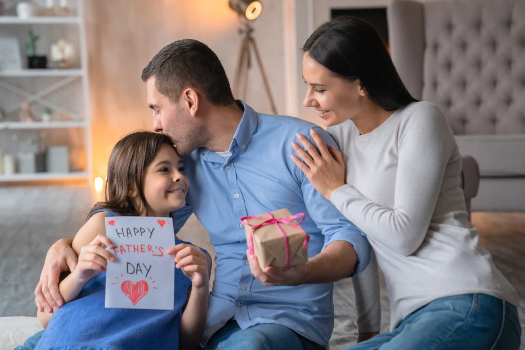 Kid gives her dad a present while they plan some Father's Day acticities
