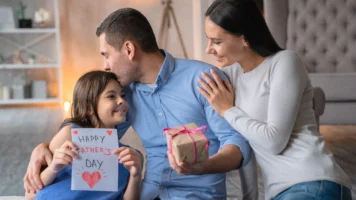 Kid gives her dad a present while they plan some Father's Day acticities