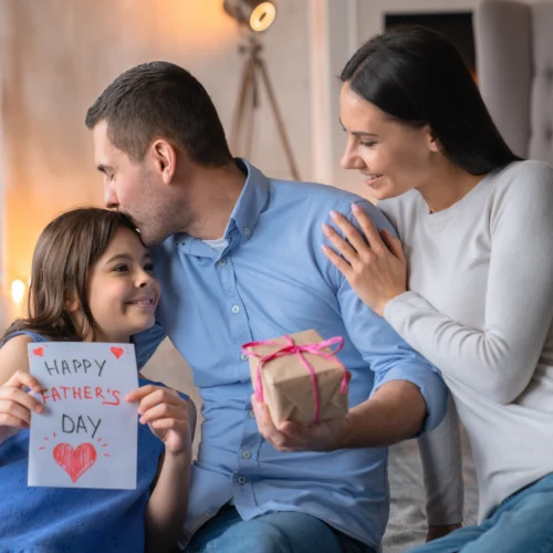 Kid gives her dad a present while they plan some Father's Day acticities