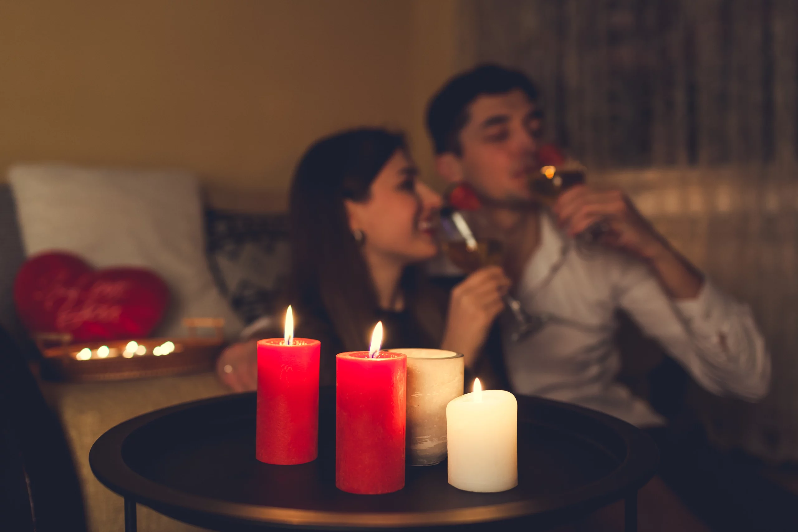 A couple enjoying a romantic night in with wine and candles with in the living room