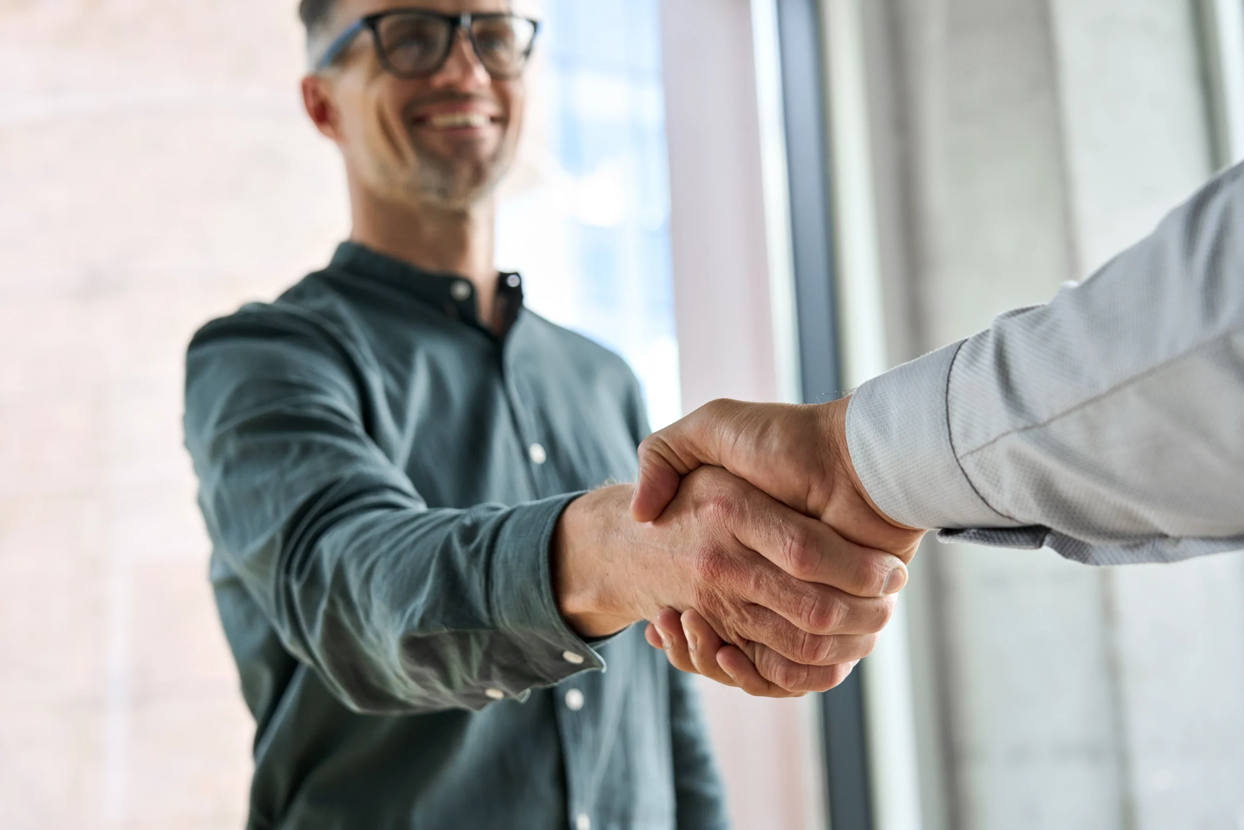 Person with glasses shaking hands with someone else out of shot
