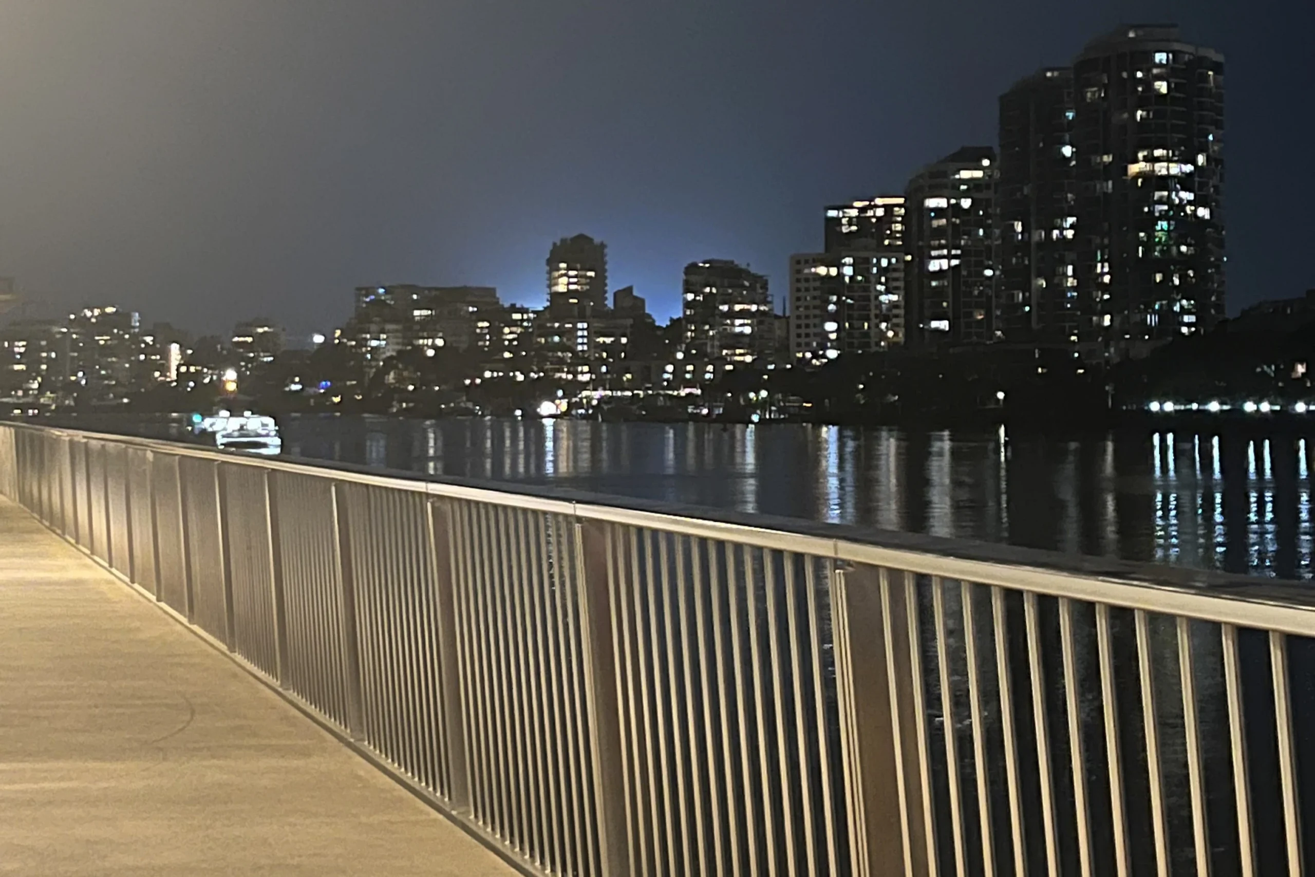 Brisbane Riverwalk at night with city lights in background