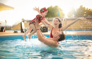 A mum and dad play with their baby in a new pool - how much will it cost to build a pool