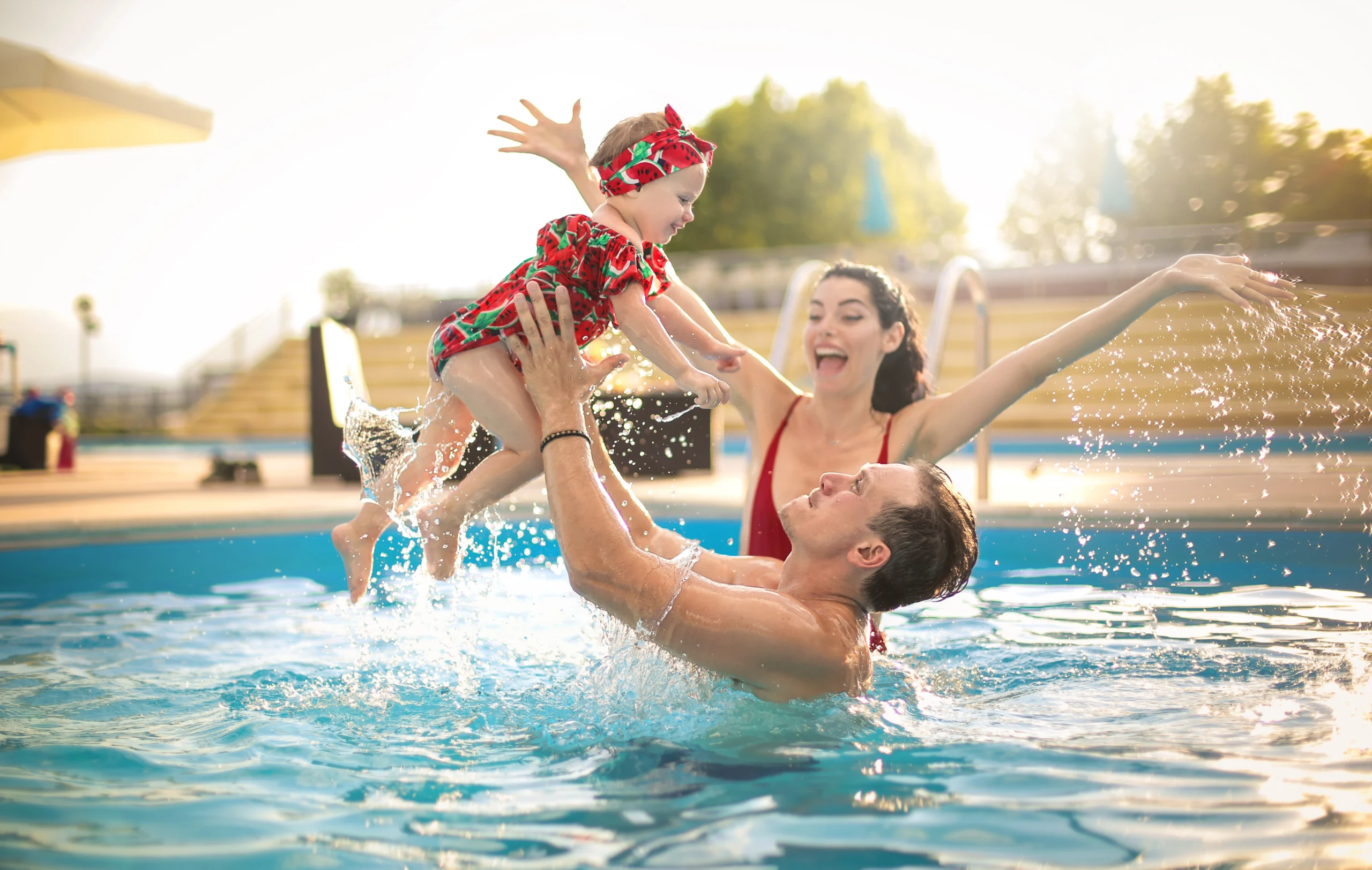 A mum and dad play with their baby in a new pool - how much will it cost to build a pool