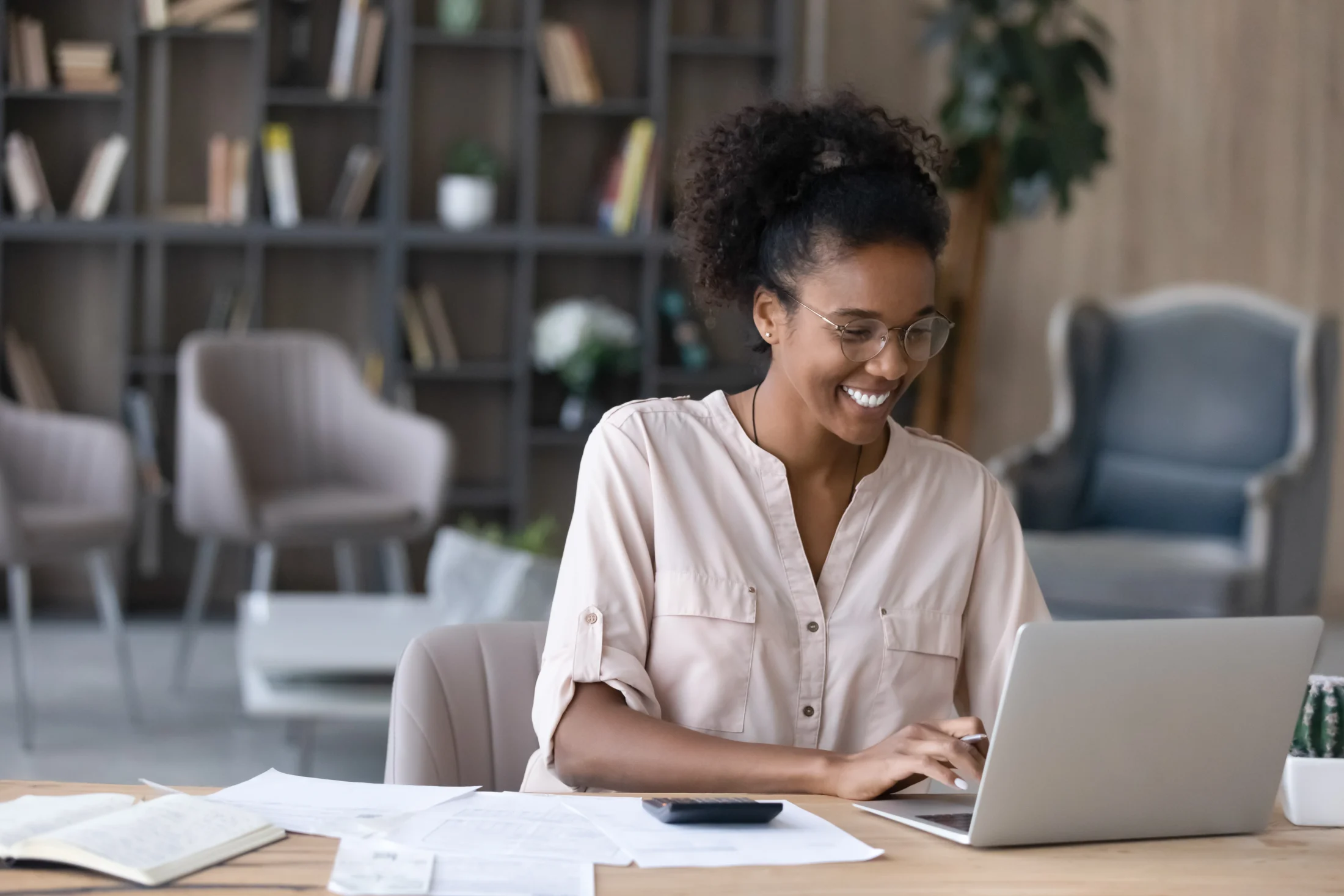Smiling woman works on her laptop figuring out how to save money long term
