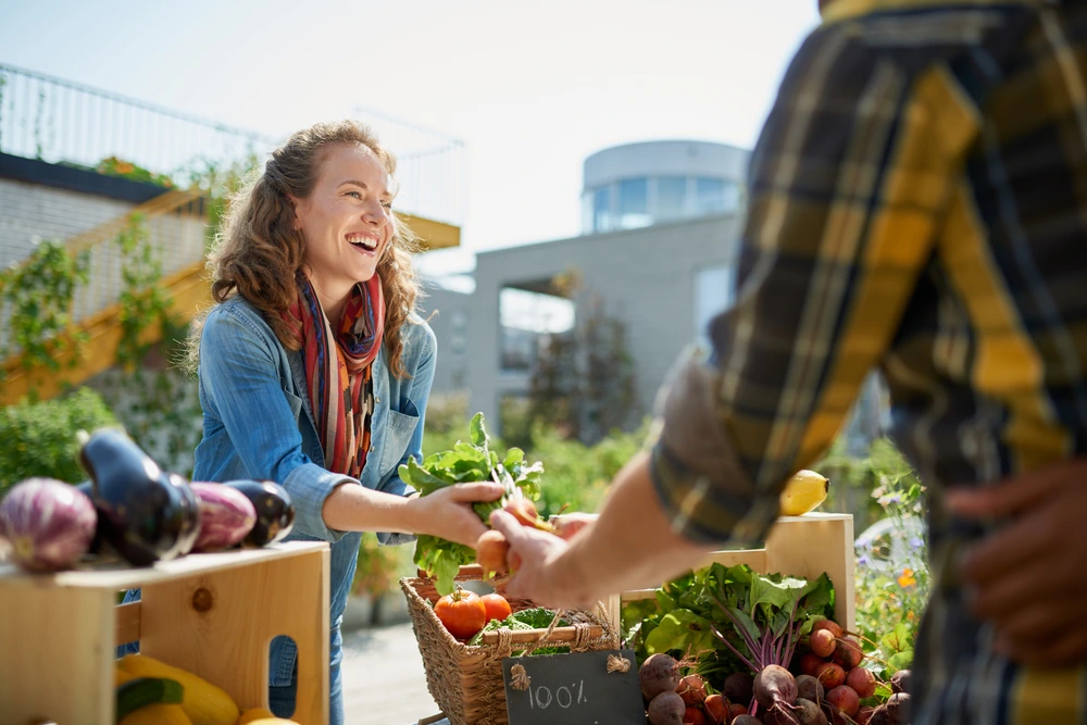 Woman buying vegetables at local market to manage money while travelling