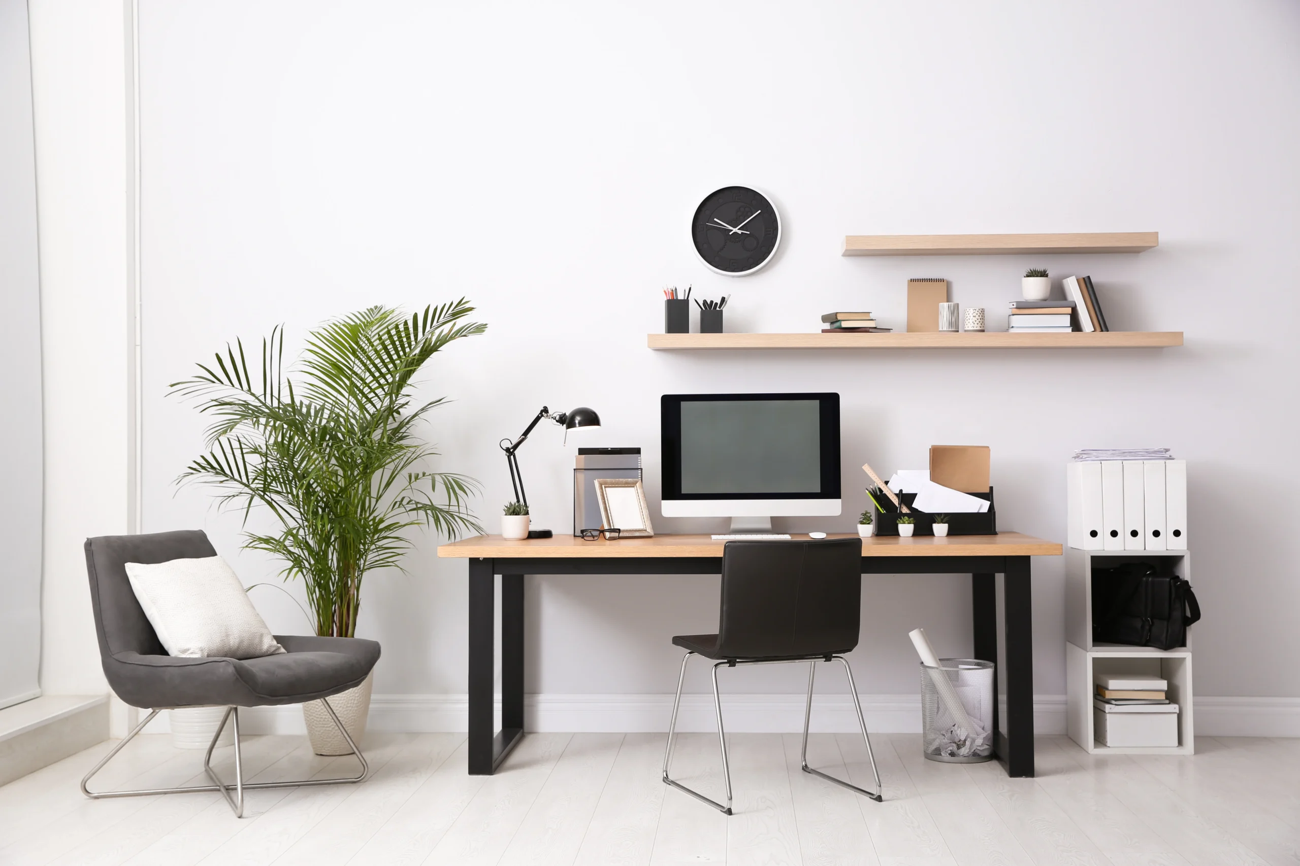 A home office set up with computer, folders, and a desk chair