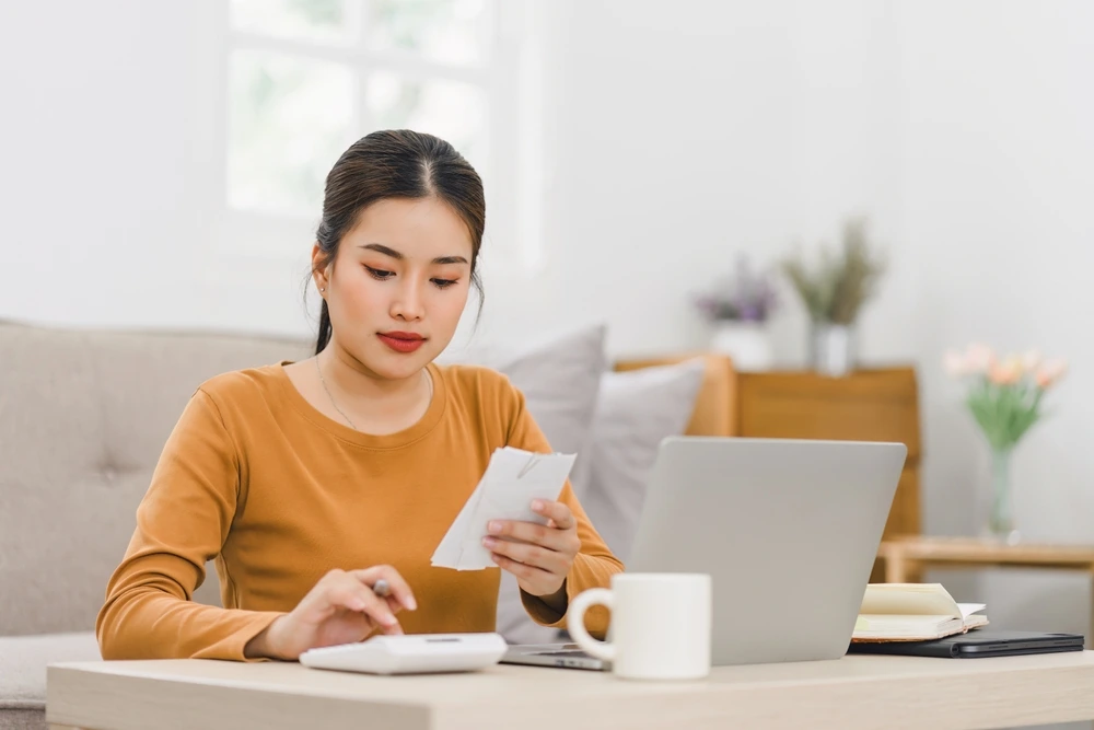 Woman calculating and writing her budget to manage her money for next holiday