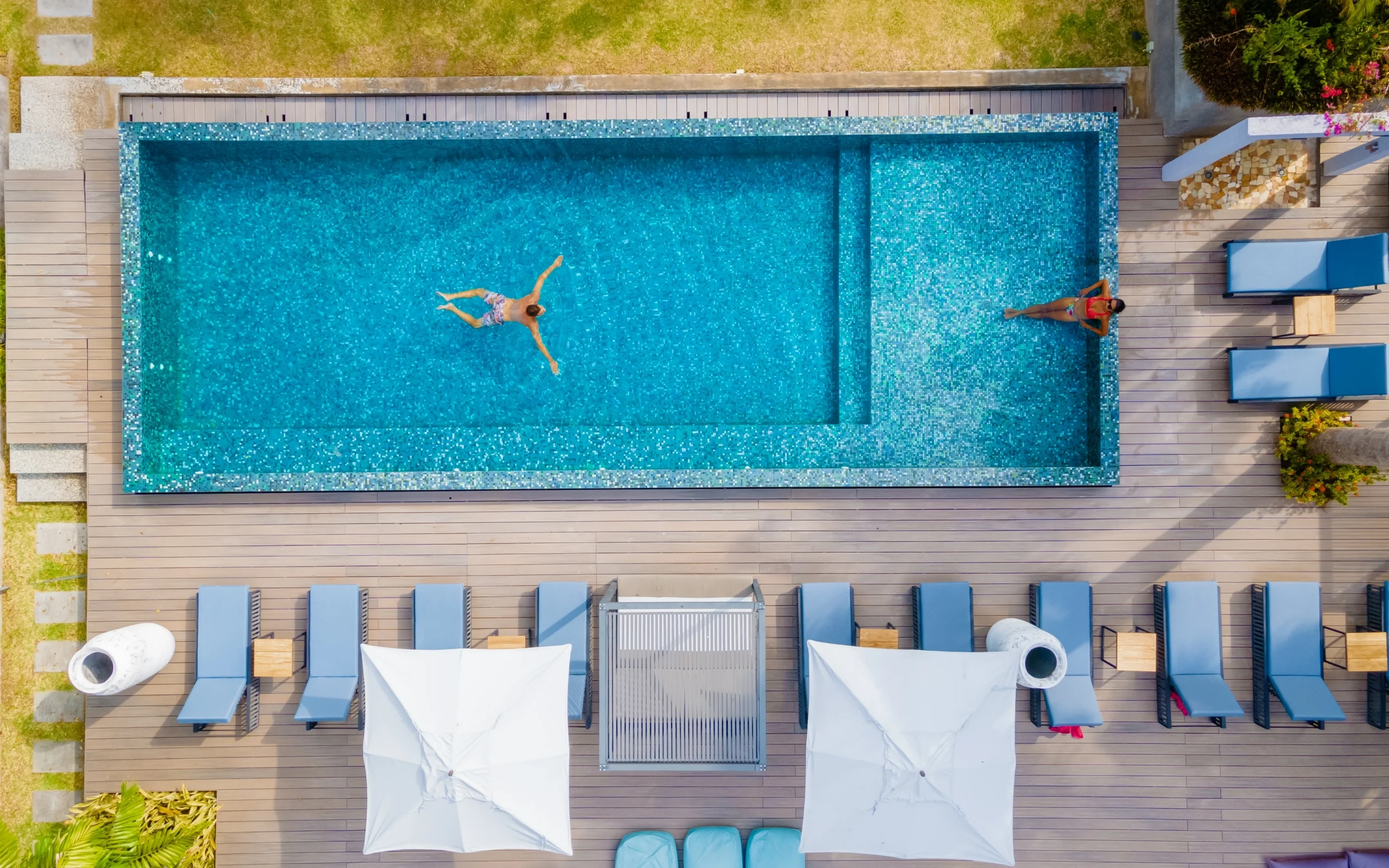Bird's eye view of a couple enjoying their new pool with a surrounding deck and lounge chairs