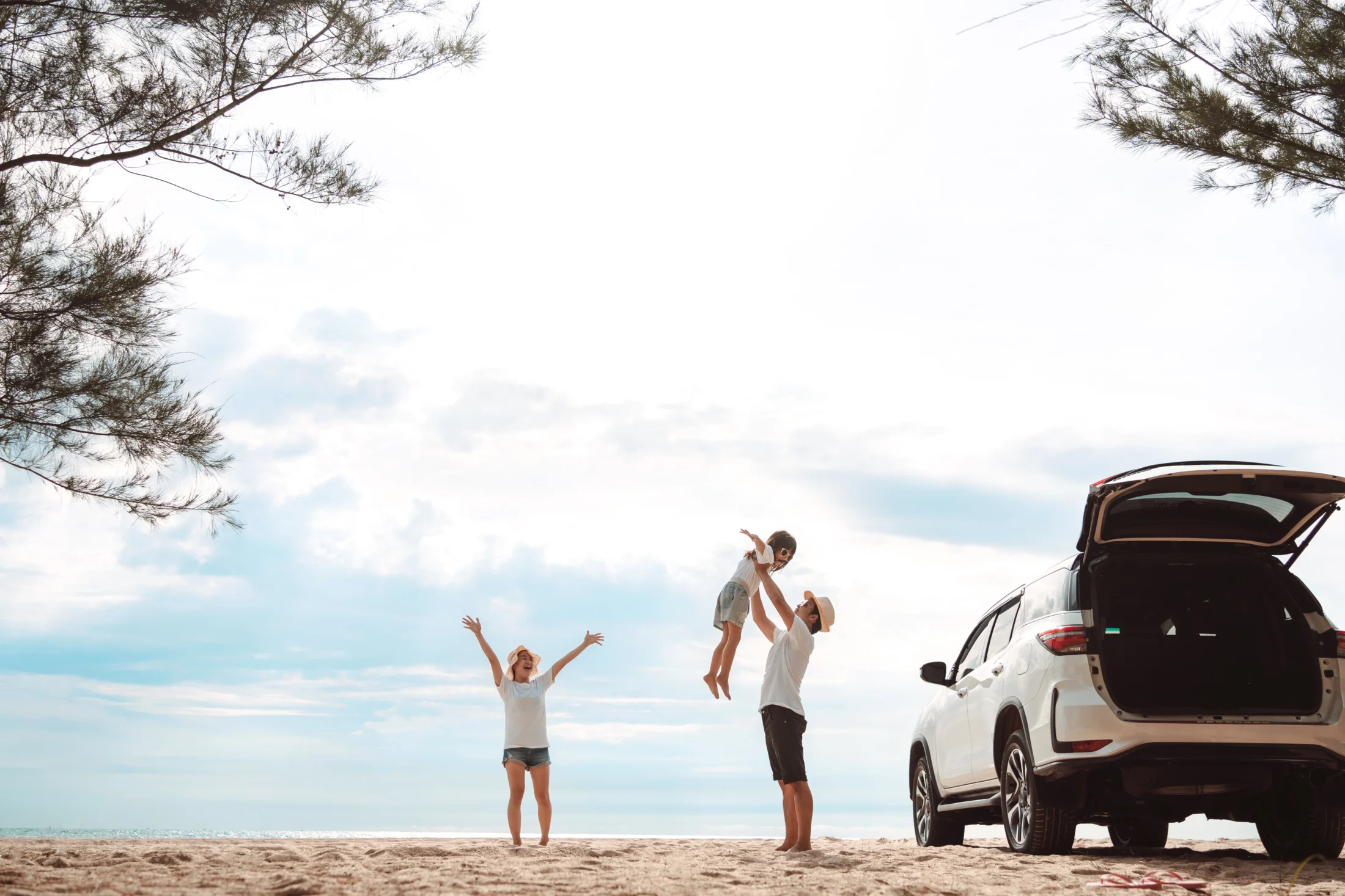 Young parents and their child celebrating a successful Labour Day road trip to a Queensland beach