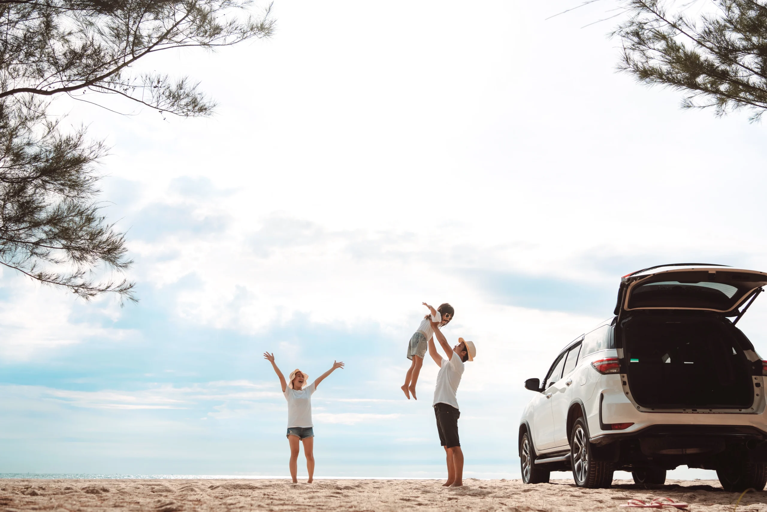 Young parents and their child celebrating a successful Labour Day road trip to a Queensland beach