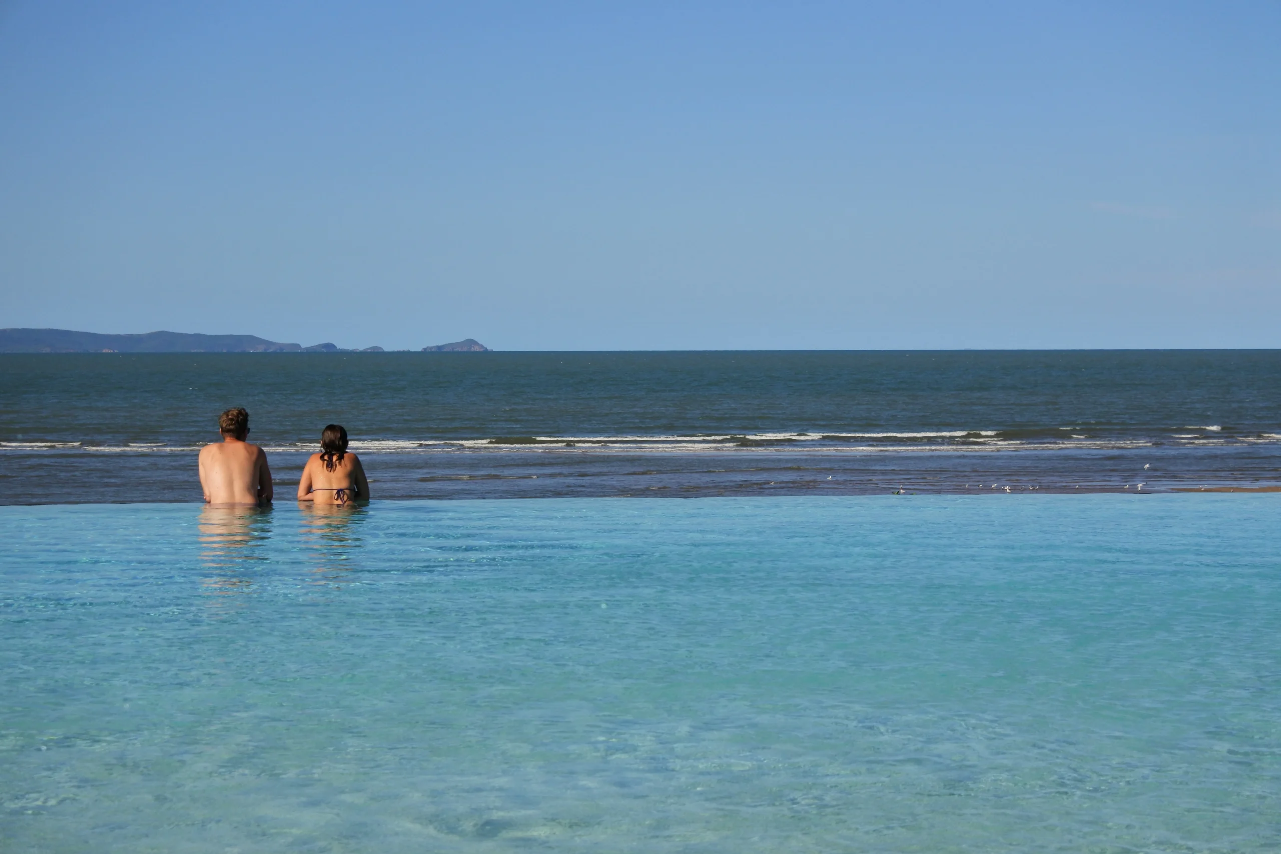 A couple look out to sea from the infinity pool in Yeppoon