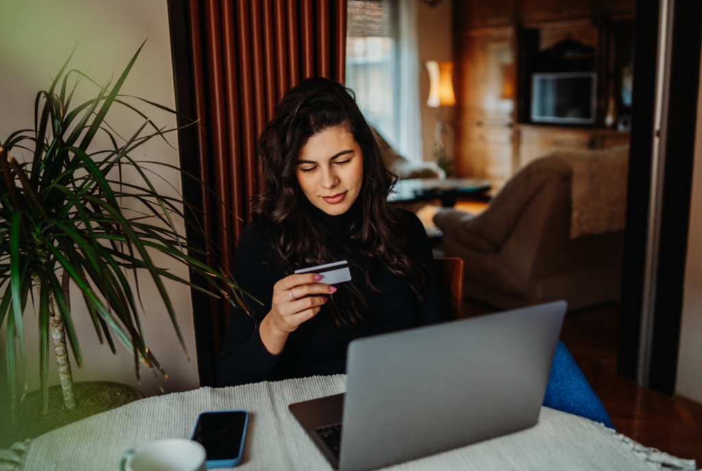 Woman holding a credit card uses her laptop to compare types of emergency loans