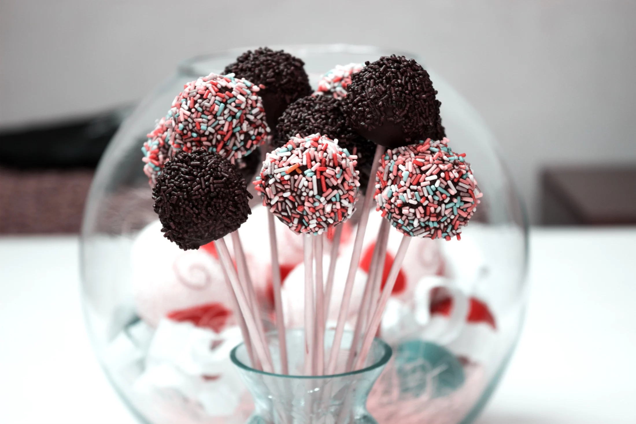 Chocolate and pastel sprinkle cake pops arranged in a glass jar, displayed as festive cheap Easter gifts for a spring celebration.