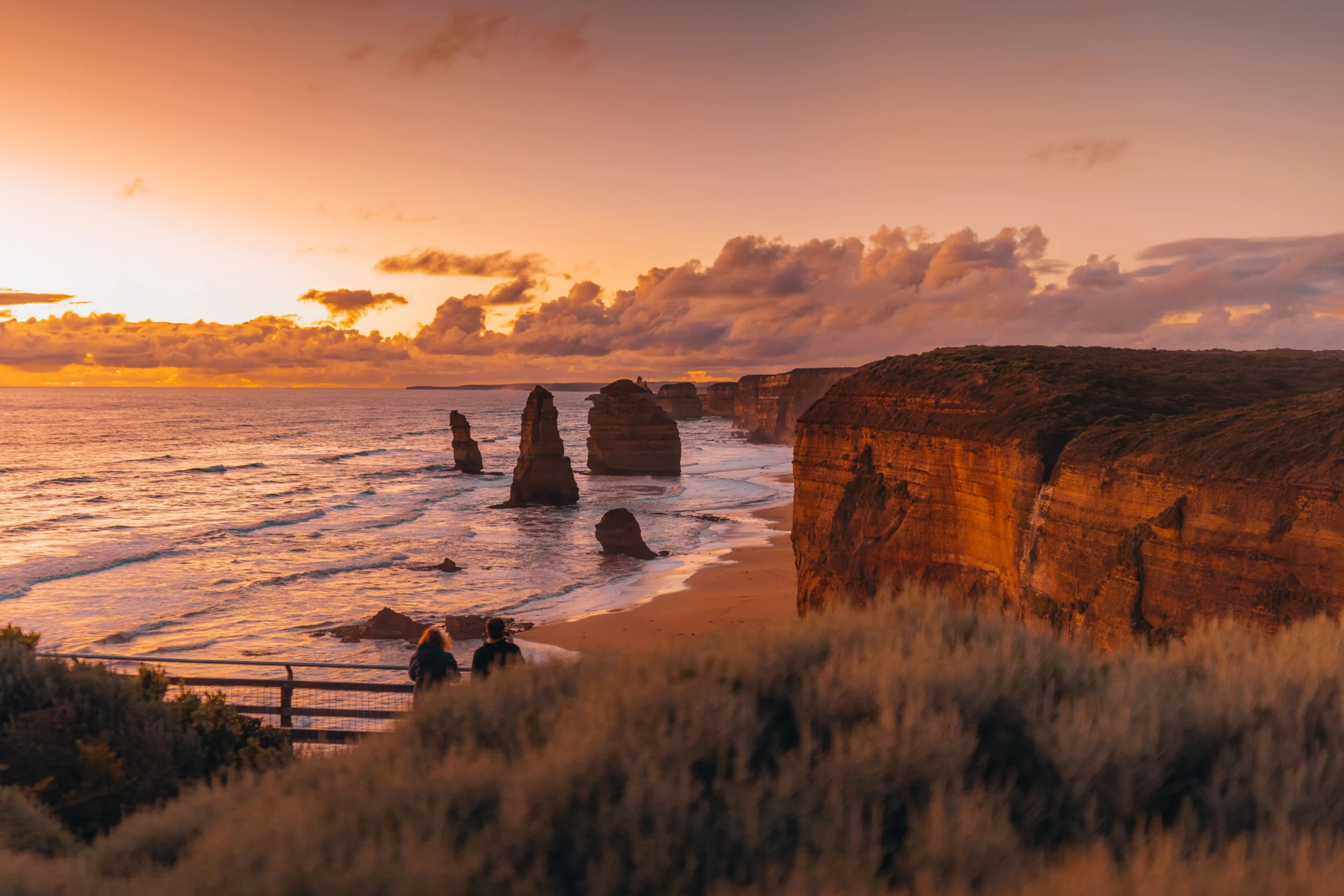 A sunset view of the Twelve Apostles along the Great Ocean Road in Victoria, with cliffs and ocean.