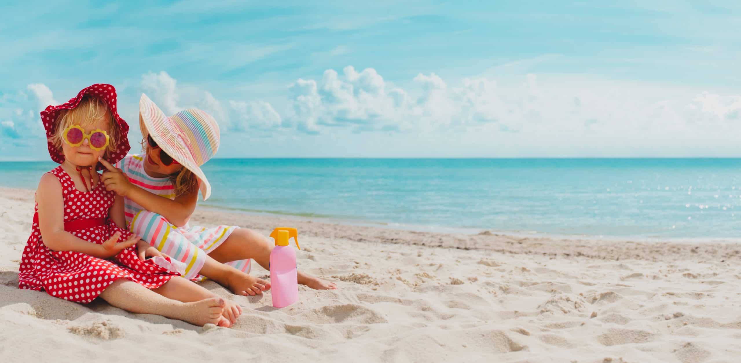 two sisters wearing hats sitting at the beach
