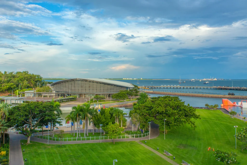 Aerial distance view of Darwin Waterfront Recreation Lagoon, surrounded by lush green trees and bright blue and cloudy sky