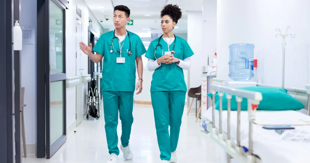Two doctors walking through a hospital emergency department together and chatting