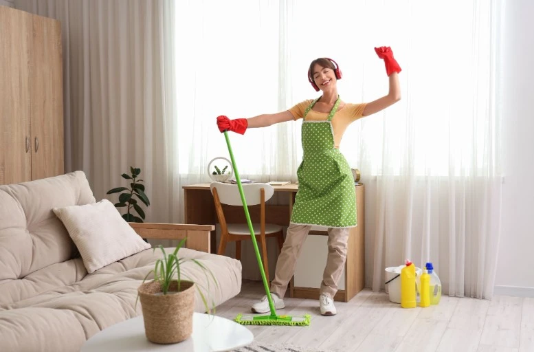 Woman cleaning her home while listening to music, representing practical ways to earn extra money or improve finances without borrowing.