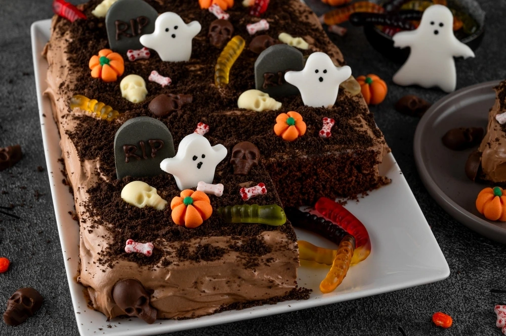Cakes that are covered in chocolate and lolly snacks to make it look like a graveyard.
