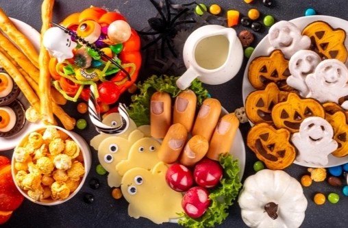 Savoury dishes for a halloween party including sausages that look like fingers, cheese cut into ghost shapes. Cookies in the shape of pumkins and bread stricks that look like witches brooms.