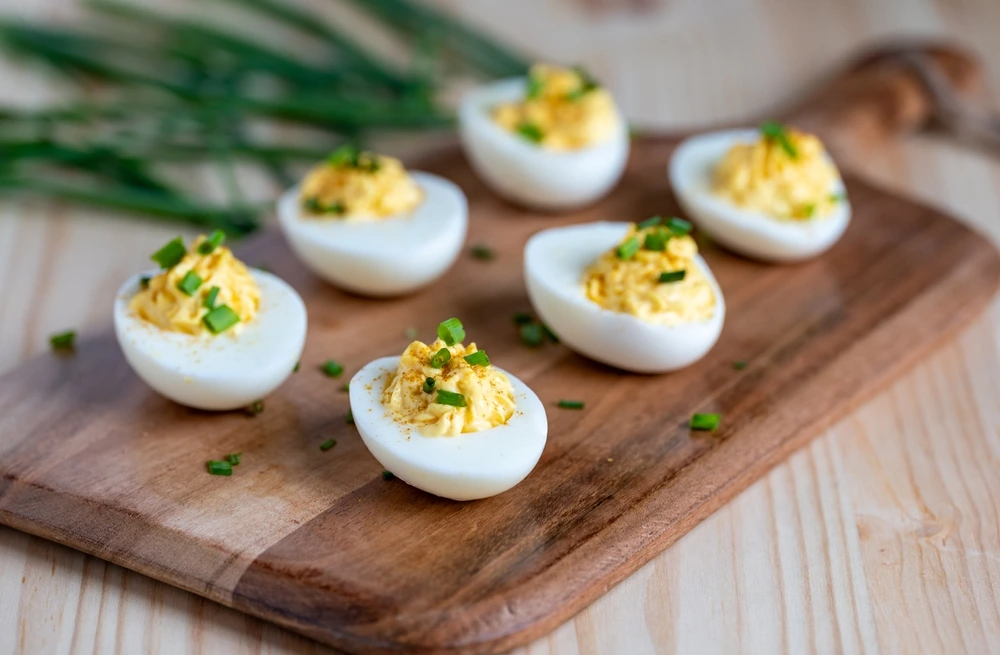 Devilled eggs served on a wooden tray for a snack before a meal.
