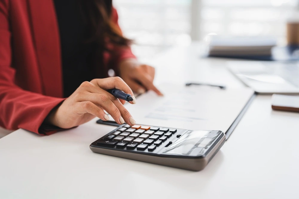 A woman calculating her monthly budget using a physical spread sheet